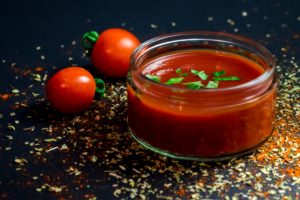 A bowl of gazpacho soup with 2 tomatoes for decoration.